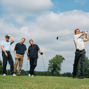 "Four men playing golf on a sunny day."