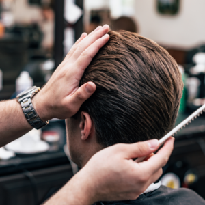 "Barber styling a man's hair in a barber shop."